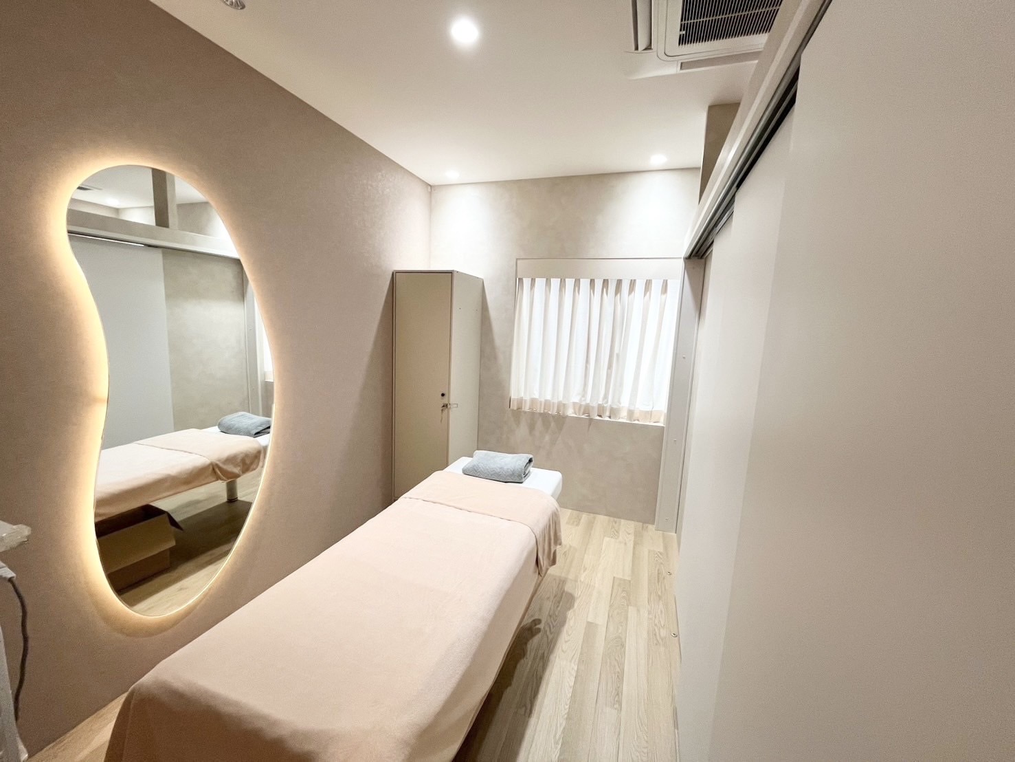 Radiance施術ルーム|有機的なバックライト付きミラーと施術ベッド